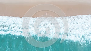 Nature abstract background beautiful sea wave on the sand beach and small tourist couple in swimsuits walking in summer holidays