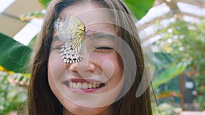 Nature, animals and girl with butterfly on face enjoying visit to garden center, plant nursery and greenhouse. Adventure