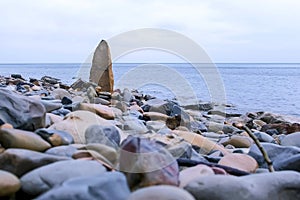 Nature background with large piece of rock on sea wild beach among stones.