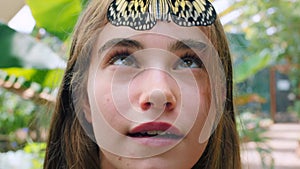 Nature butterfly, happy and face of woman on travel adventure journey in insect sanctuary. Green tree leaf, forehead and