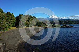 Nature of Chile, Beautiful landscape, Dark volcanic sand beach on Villarrica lake, snow capped Villarrica volcano, Pucon
