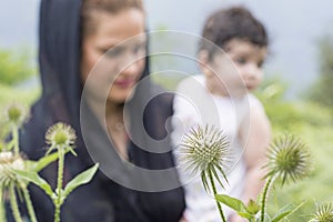 Nature exploration concept mother and young child in outdoor environment focus at foreground plants