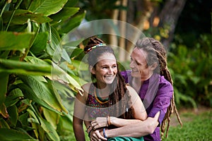 Nature, hipster and couple hugging in garden on outdoor romantic date together for bonding. Smile, love and happy rasta