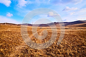 Nature landscape with golden glass, old rural road, hills and blue sky with white clouds on background in a nice day or