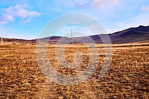 Nature landscape with golden glass, old rural road, hills and blue sky with white clouds on background in a nice day or