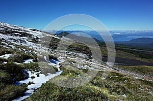 Nature landscape, Grass and snow on mountainside of Villarrica volcano, clear blue sky