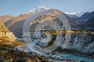 Hunza river flowing through Karakoram mountain range against clear blue sky.