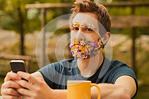 Nature lover with flower beard uses phone