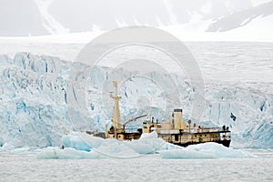 Nature lovers in Arctic Svalbard, Norway. Motor boat with tourists on the ice sea, snowy mountain in background. Arctic cruise in