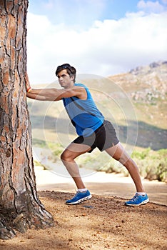 Nature, man or runner stretching legs for fitness training, wellness or exercise outdoors by a tree. Relax, muscle