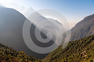 Nature in Nepal, high mountains with a trees in a shadow on a blue sky background.