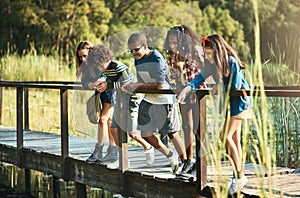 Nature is the new classroom. Shot of a group of teenagers standing on a bridge in nature at summer camp.