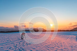 Nature photographer on a snowy field at sunset time
