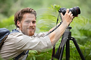 nature photographer photographing forest with camera on tripod photo