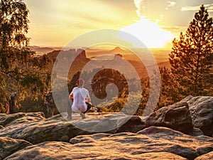 Nature photographer takes photos on peak of rock.