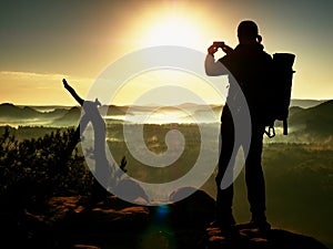 Nature photographer takes photos on peak of rock.