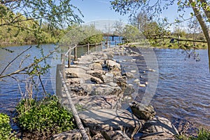 Nature reserve with Oude Maas river, stepping stones at Brug Molenplas with wooden posts and rope fences