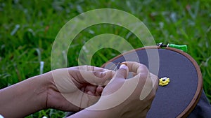 Nature\'s Stitch: Woman Crafting Flowers on Hoop in the Green Serenity