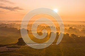 Nature scenery with sun rising above country covered in fog.