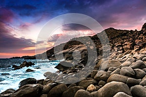 Nature Seascape with Eggshaped Rocks on A Wild Beach, Waves and Rocky Mountains at Dramatic Sunset photo