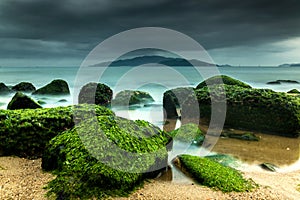 Nature Seascape with Green Moss Covered Rocks at Beach and Dark, Dramatic Sky during A Storm