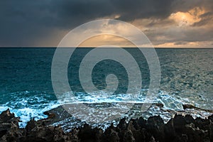 Nature Seascape with Rough Rocks, Waves, Dark Clouds and Sky during A Storm at Sunrise