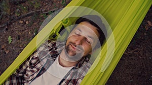 Nature travel and vacation theme. Close-up of happy caucasian young man resting with closed eyes and smiling in green