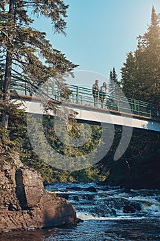 Nature is the ultimate breakaway. a young couple standing on a bridge surrounded by nature.