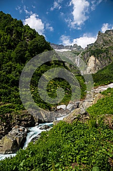 Nature view, cool mountain river stream flowing from under the g