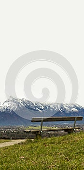 Nature wallpaper background scenic view Alps mountains hill with wooden bench white sky empty copy space for your text, vertical