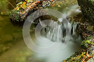 Nature waterfall at mountain river cascade. Colorful green mossy rocks, waterfall and cascade. Nature background.