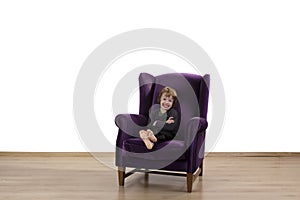 Naught child sitting with arms crossed on armchair photo