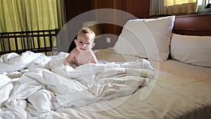 Naughty baby lies on the bed in the diaper and screams