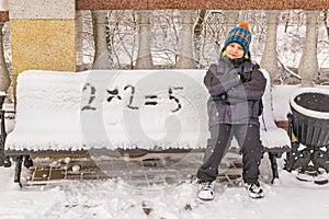 Naughty boy wrongly decides an example on a snow-covered bench