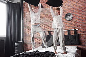 Naughty children Little boy and girl staged a pillow fight on the bed in the bedroom. They like that kind of game