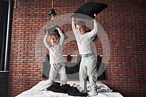 Naughty children Little boy and girl staged a pillow fight on the bed in the bedroom. They like that kind of game