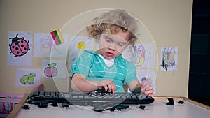 Naughty little child destroy computer keyboard on table