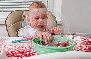 Naughty messy dirty baby is eating with hands