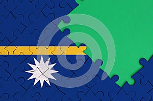 Nauru flag is depicted on a completed jigsaw puzzle with free green copy space on the right side