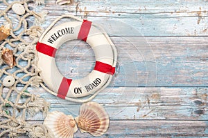 Nautica background with safety buoy with the text welcome on board seashells and fishing net on a blue scaffolding wooden backgrou