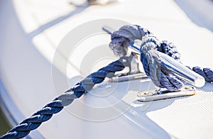 Nautical background, blue rope knotted on cleat of boat deck