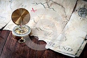 Nautical compass in front of fake pirates treasure map on wooden table