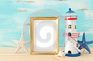 Nautical concept with empty photo frame and lighthouse over wooden table. For photography montage