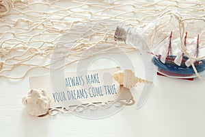 nautical concept image with sail boat in the bottle and note: ALWAYS MAKE YOUR DREAMS COME TRUE.