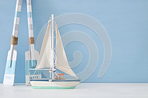 nautical concept with white decorative sail boat and wooden oars over blue background.