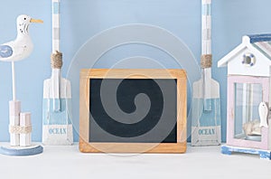 nautical concept with white decorative seagull bird, boat oars, beach house and empty blackboard over blue background.