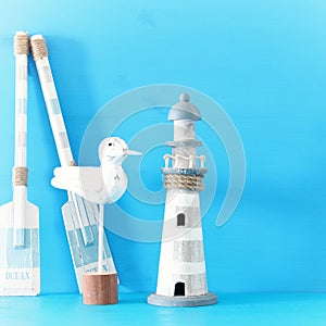 nautical concept with white decorative seagull bird, lighthouse and wooden boat oars over blue background.