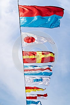 Nautical flags against blue sky in the wind at sunny day, vertical