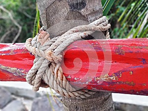 Nautical knot in red wood mast tied to palm tree trunk. Tropical and Caribbean culture. Detail of traditional boats. Safety and