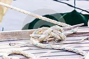Nautical rope tied on cleat at wooden deck of boat